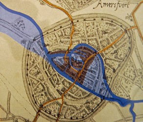 <p>Amersfoort in de 12e eeuw. In donkerblauw zijn de waterlopen zichtbaar gemaakt, lichtblauw zijn natte gebieden. In geel zijn de doorgaande routes weergegeven en het donkere gebied was bewoond [M. Krauwer en F. Snieder, <em>Nering en vermaak, de opgraving van een veertiende-eeuwse markt in Amersfoort</em>,  p.18]. </p>
